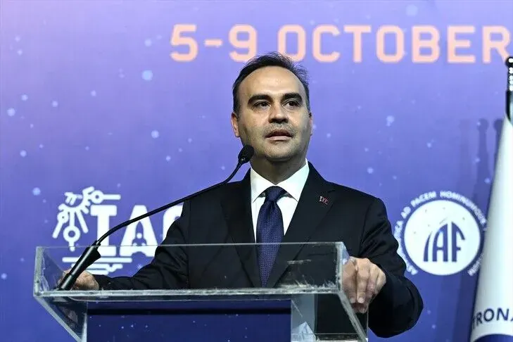Koyu renkli metal ve cam malzemeden üretilmiş, tepesinde sıcak bir ışık yanan soyut heykel