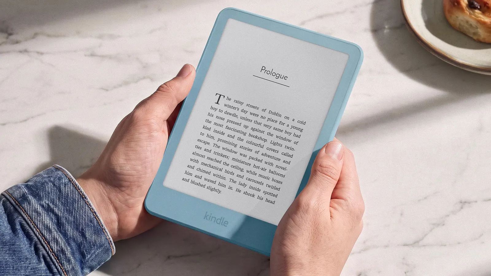 Gri yüzey üzerinde sergilenen yeni nesil ince Kindle e-okuyucu ve uzaktan kumanda