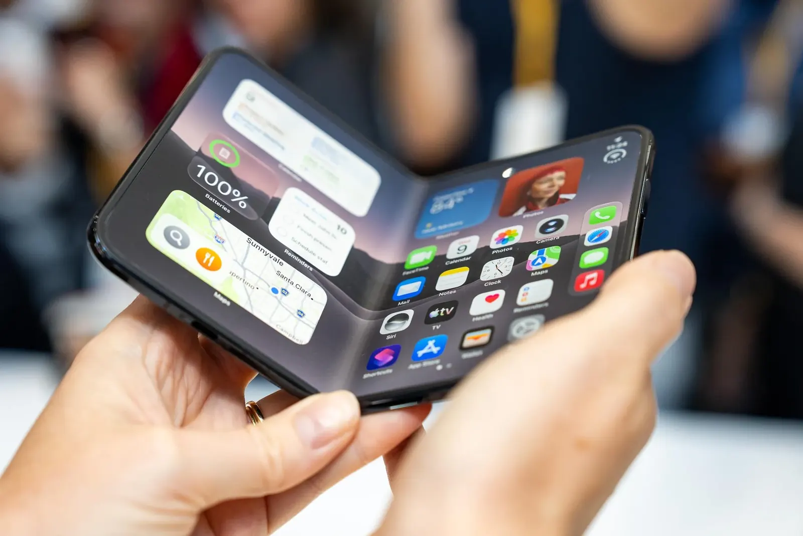 Koyu zemin üzerinde duran katlanabilir ekranlı telefon ve ışık yansımaları